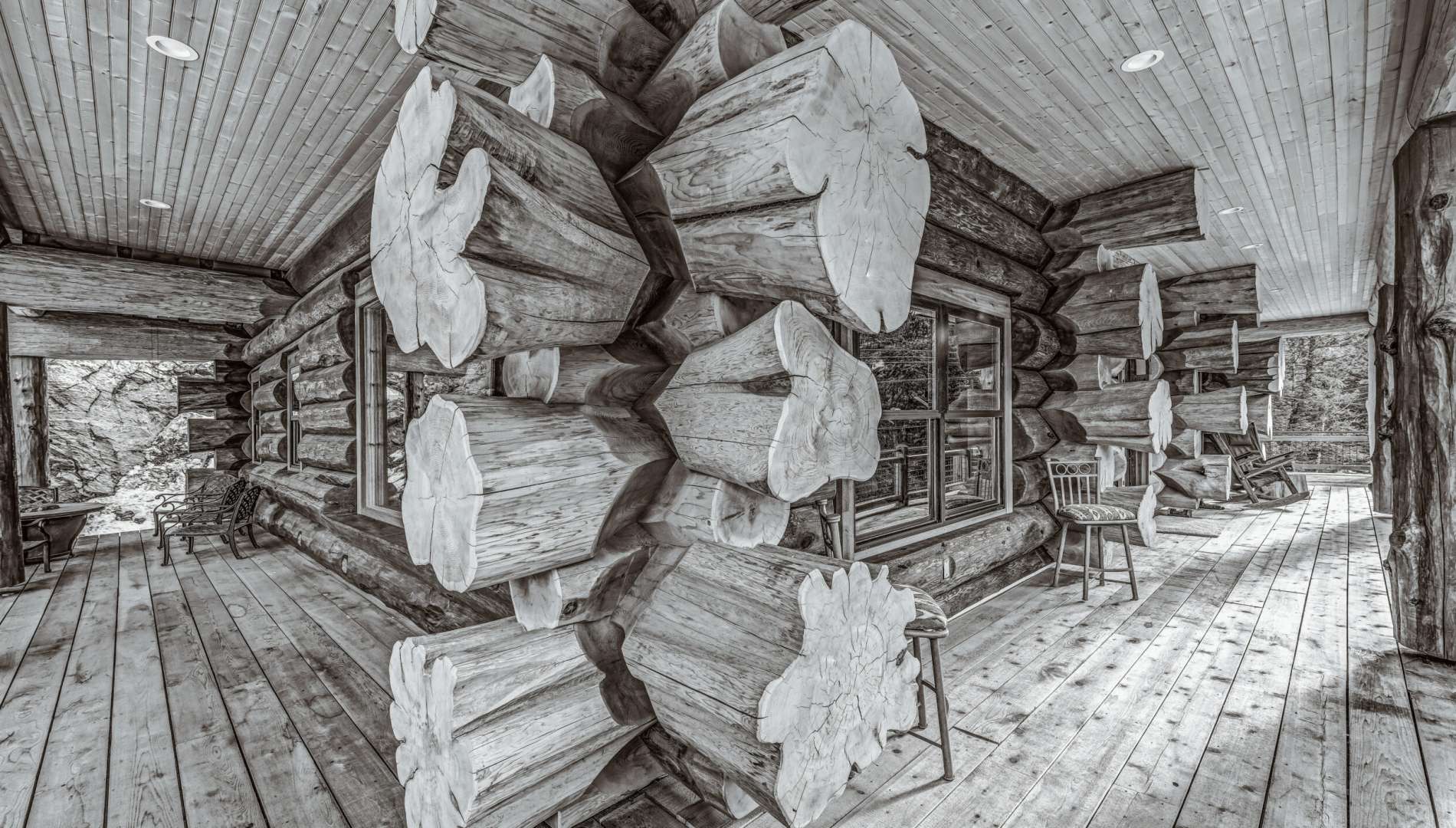 Detail of handcrafted Western Red Cedar log joinery on covered porch in Colorado with flared log ends and rustic wood decking