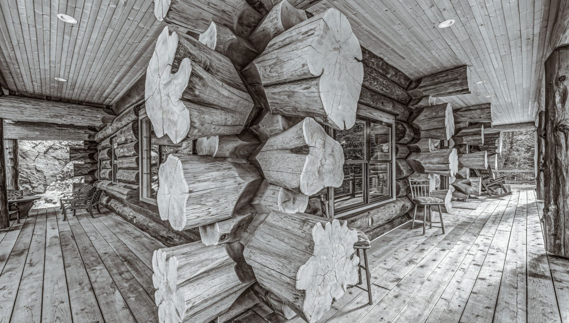 Detail of handcrafted Western Red Cedar log joinery on covered porch in Colorado with flared log ends and rustic wood decking