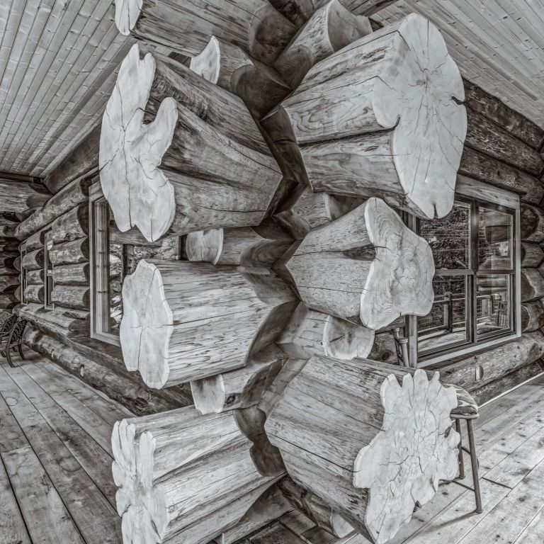 Detail of handcrafted Western Red Cedar log joinery on covered porch in Colorado with flared log ends and rustic wood decking